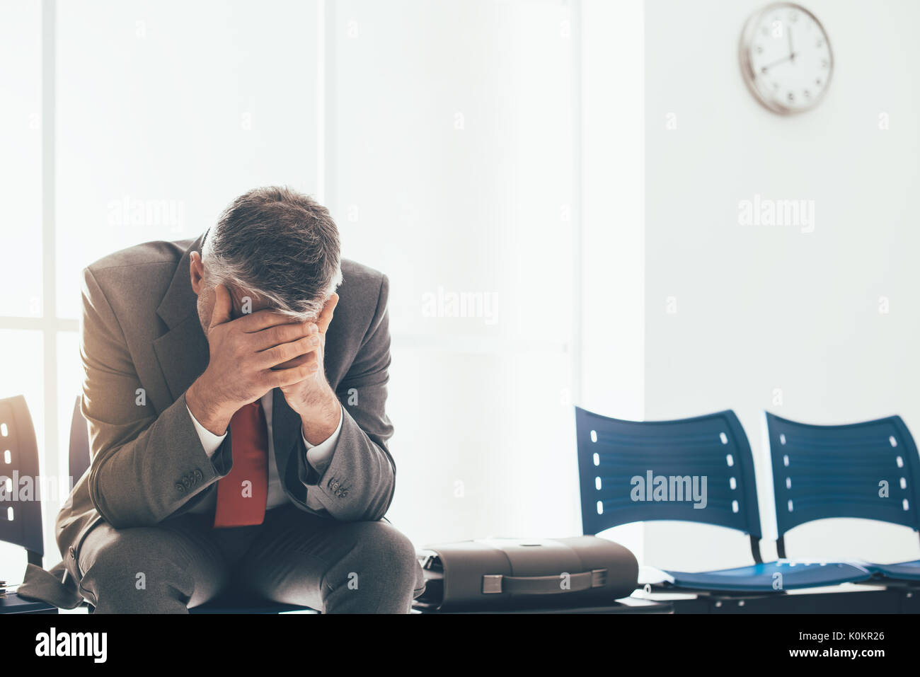 Desperate businessman dans la salle d'attente avec la tête dans les mains, il est en attente d'une entrevue d'emploi, le chômage et l'échec de l'entreprise concept Banque D'Images