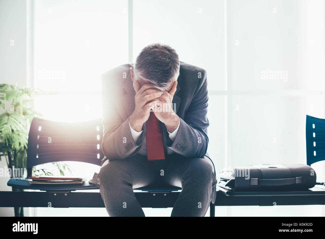 Desperate businessman dans la salle d'attente avec la tête dans les mains, il est en attente d'une entrevue d'emploi, le chômage et l'échec de l'entreprise concept Banque D'Images