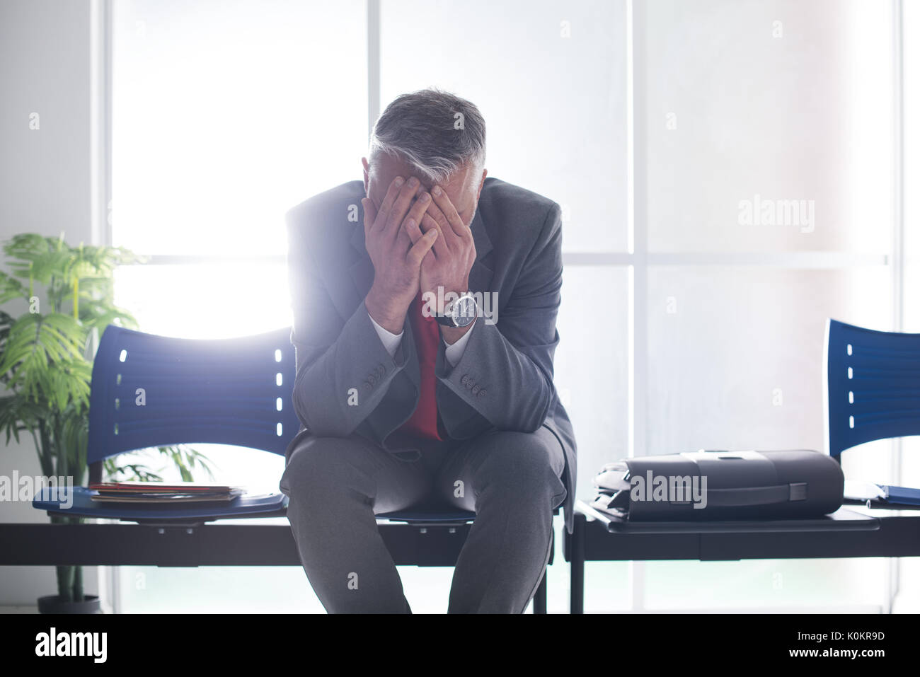 Desperate businessman dans la salle d'attente avec la tête dans les mains, il est en attente d'une entrevue d'emploi, le chômage et l'échec de l'entreprise concept Banque D'Images