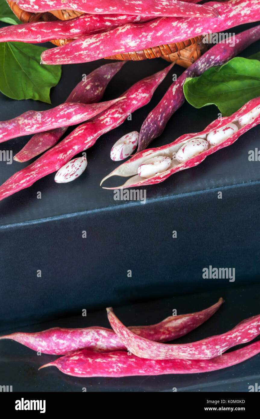 Haricots rouges en dosettes sur un fond sombre. les fèves de couleur avec des feuilles close up Banque D'Images