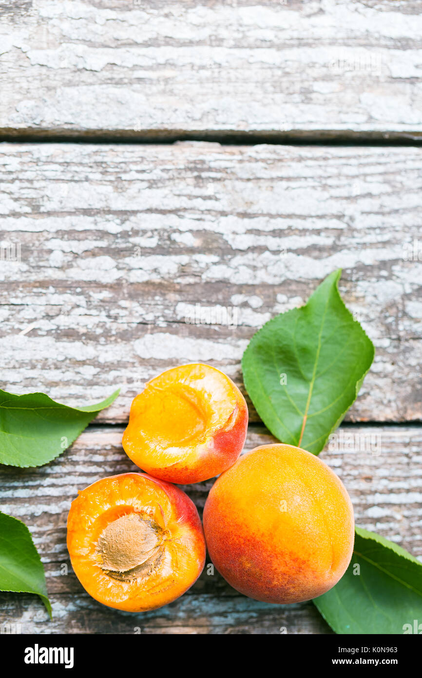 Belle orange mûre abricots avec les feuilles des vieux panneaux de bois sur un fond de la nature Banque D'Images