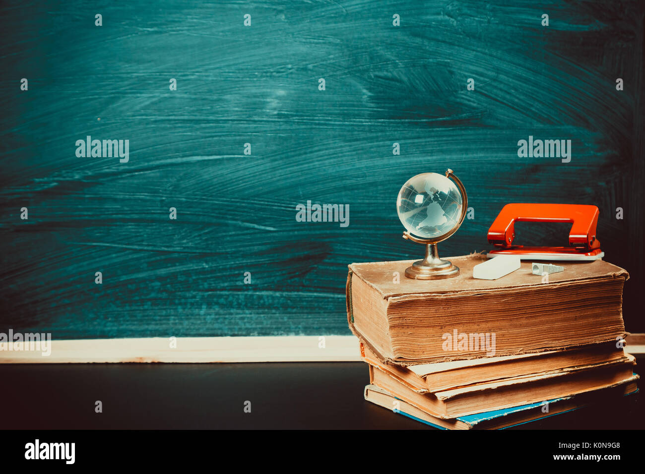 Vieux tableau noir avec des craies, des livres, un globe et un crayon. Une belle toile de fond pour l'éducation, un espace libre pour votre texte. retour à l'école. shallow dof. Banque D'Images