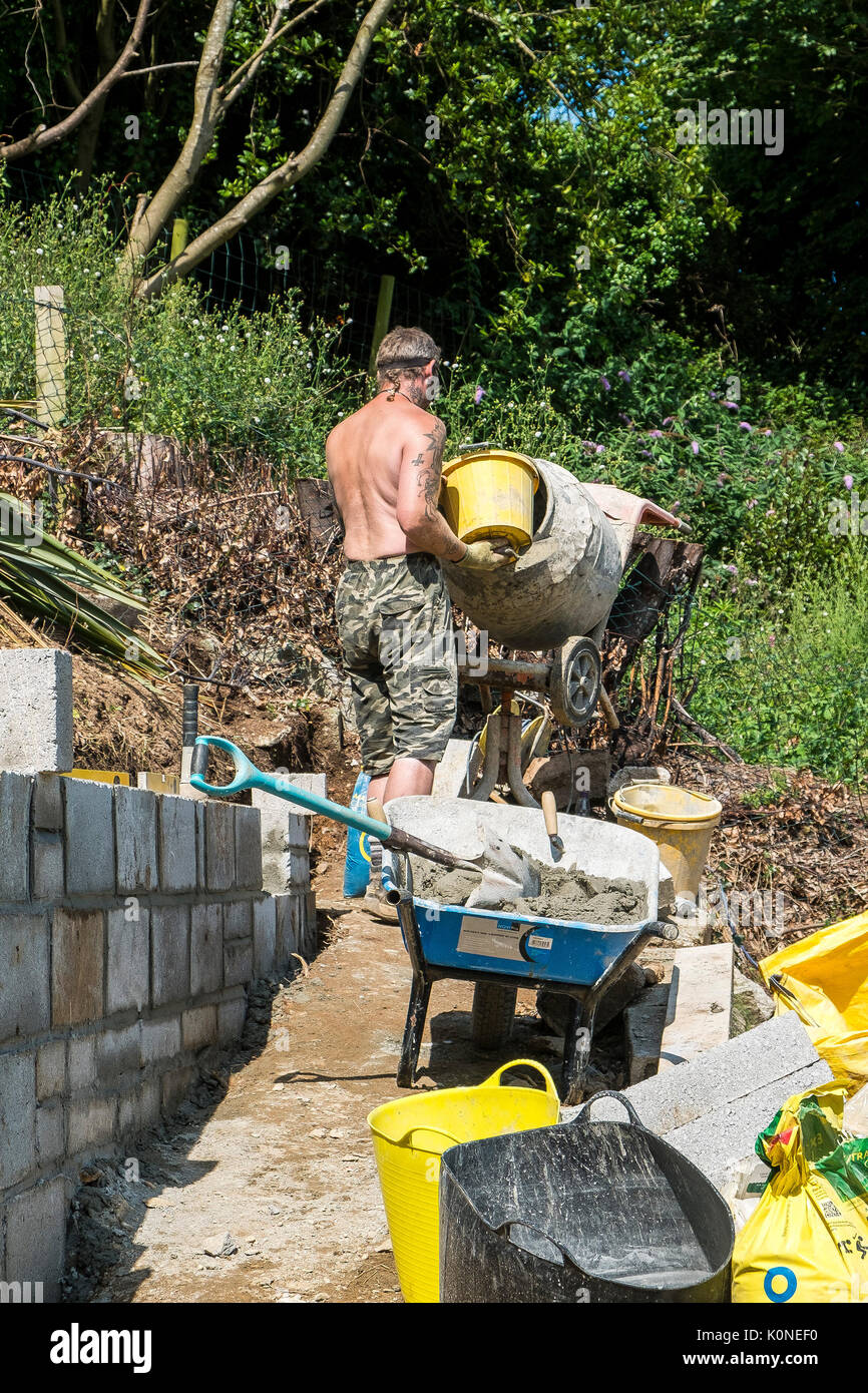 Un travailleur à l'aide d'une bétonnière sur un chantier de construction. Banque D'Images