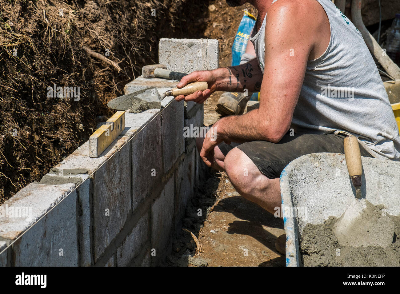 Les travailleurs qui construisent un mur de bloc sur un chantier de construction. Banque D'Images