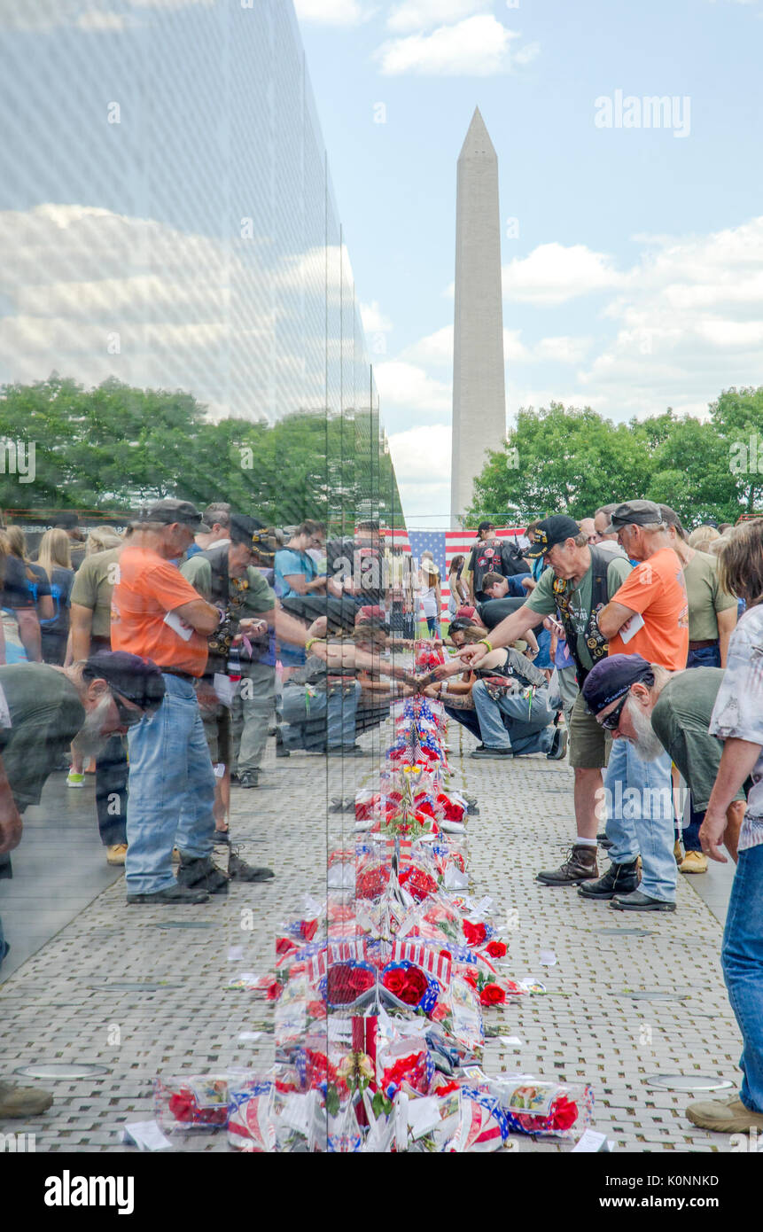 Les visiteurs regarder les noms et les objets laissés à la Vietnam Veterans Memorial wall à Washington DC. Banque D'Images