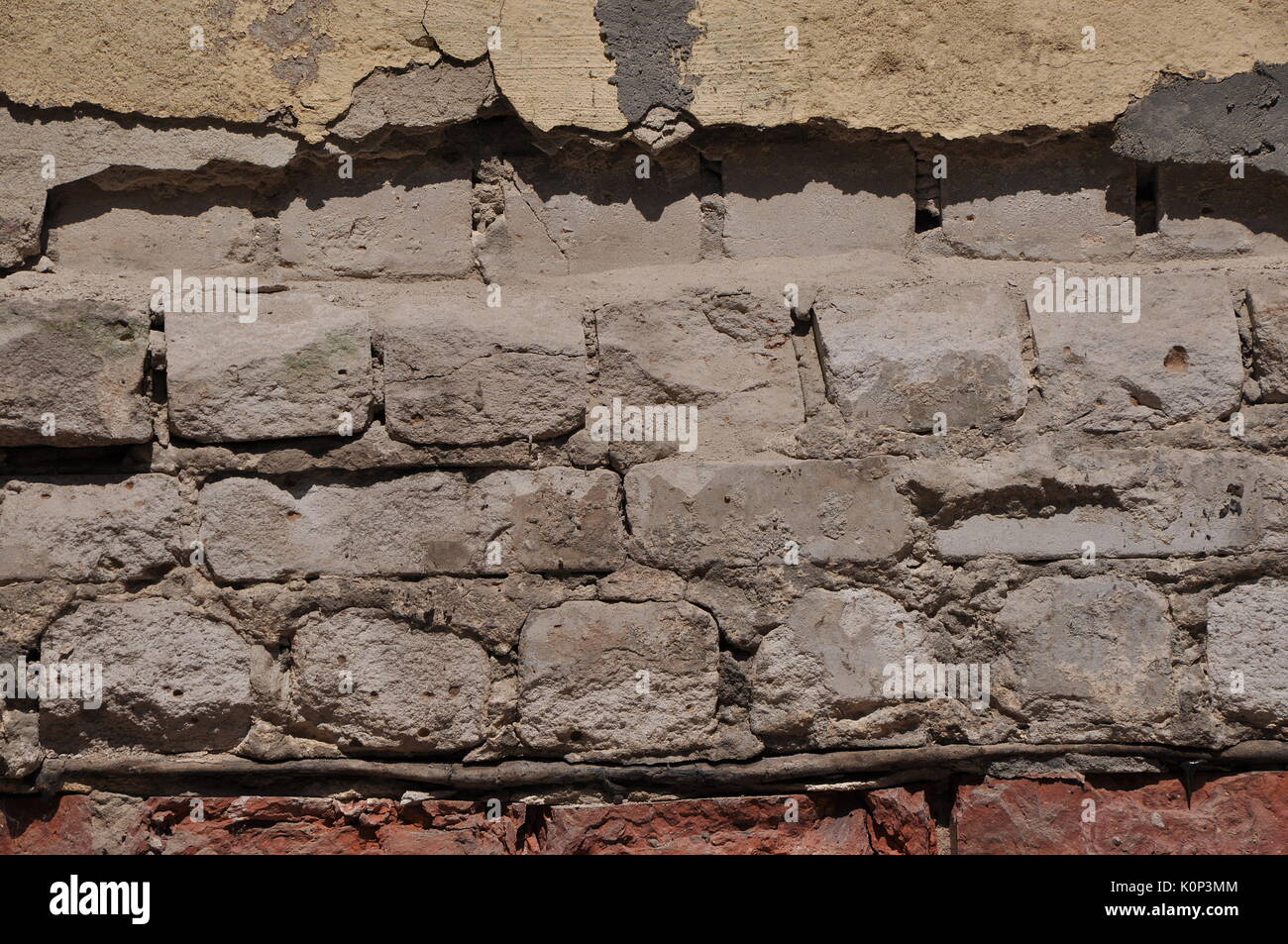 La façade de l'immeuble négligé close-up avec ruiné et écrasé en plâtre blanc et rouge brique. Banque D'Images