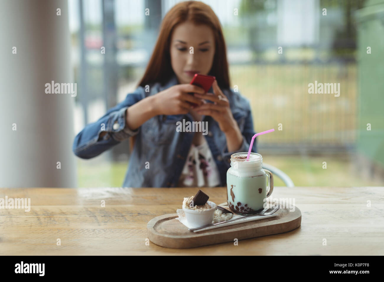 Photographier une femme boire et un dessert sur le plateau de la table en position assise dans le café Banque D'Images