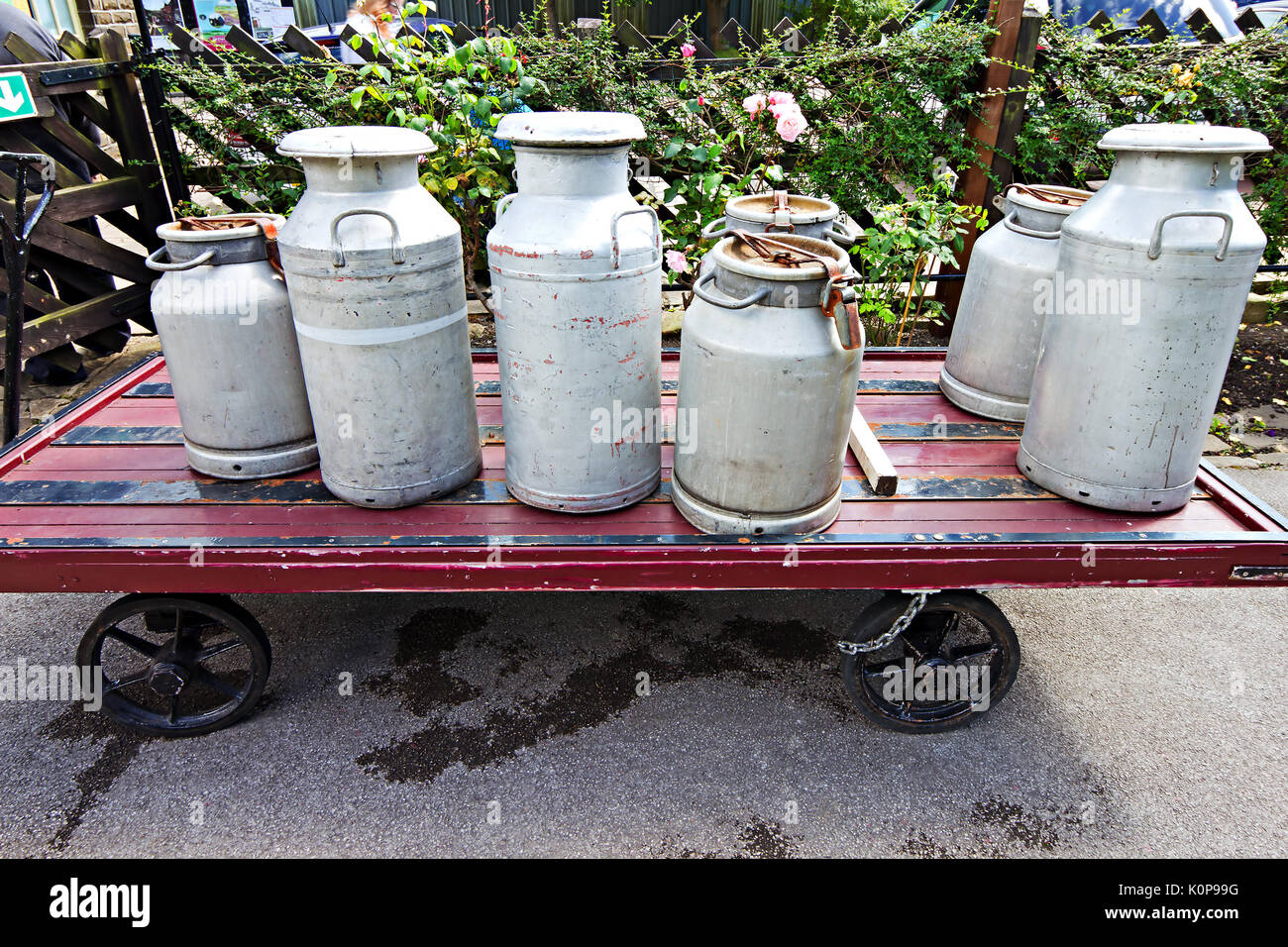 Les bidons de lait à l'ancienne sur un panier à Ferme de la station sur le chemin de fer de la vallée de Keighley et Worth, West Yorkshire, Angleterre, Royaume-Uni. Banque D'Images