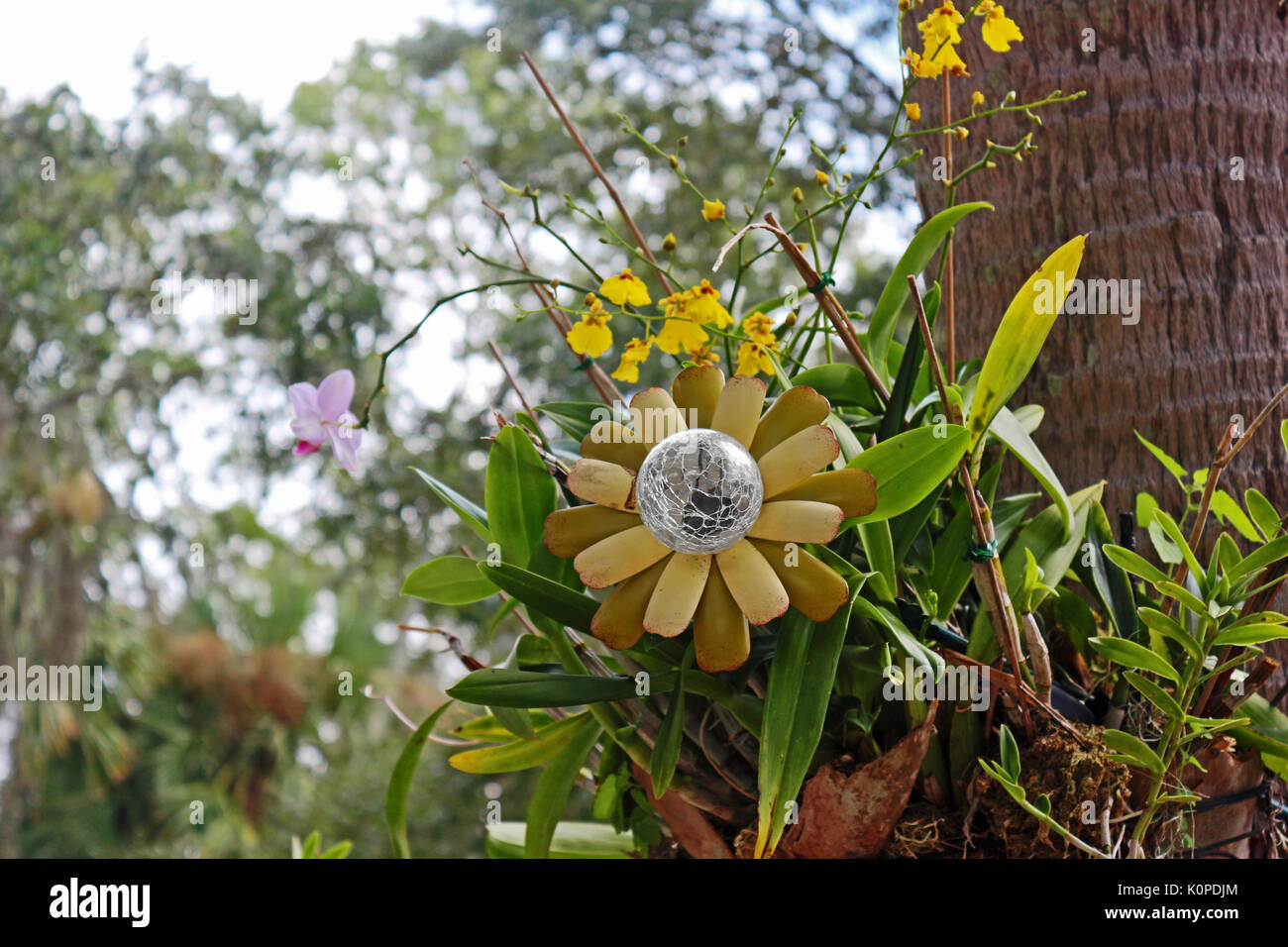 Un artiste affichant le verre / métal fleur parmi les fleurs réelles Banque D'Images