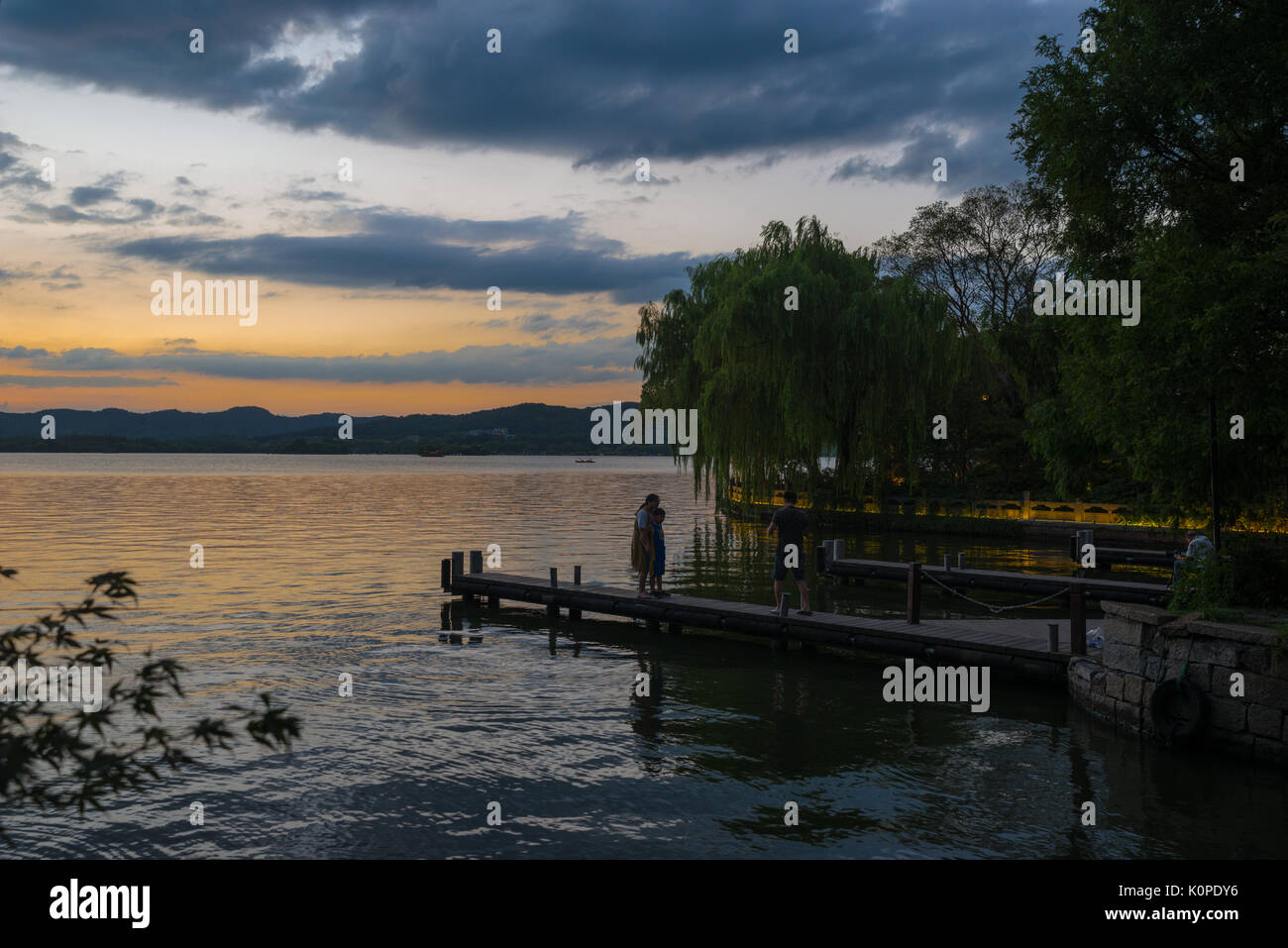 Des gens qui font des choses par le lac, le soir, heureux de franchise Banque D'Images