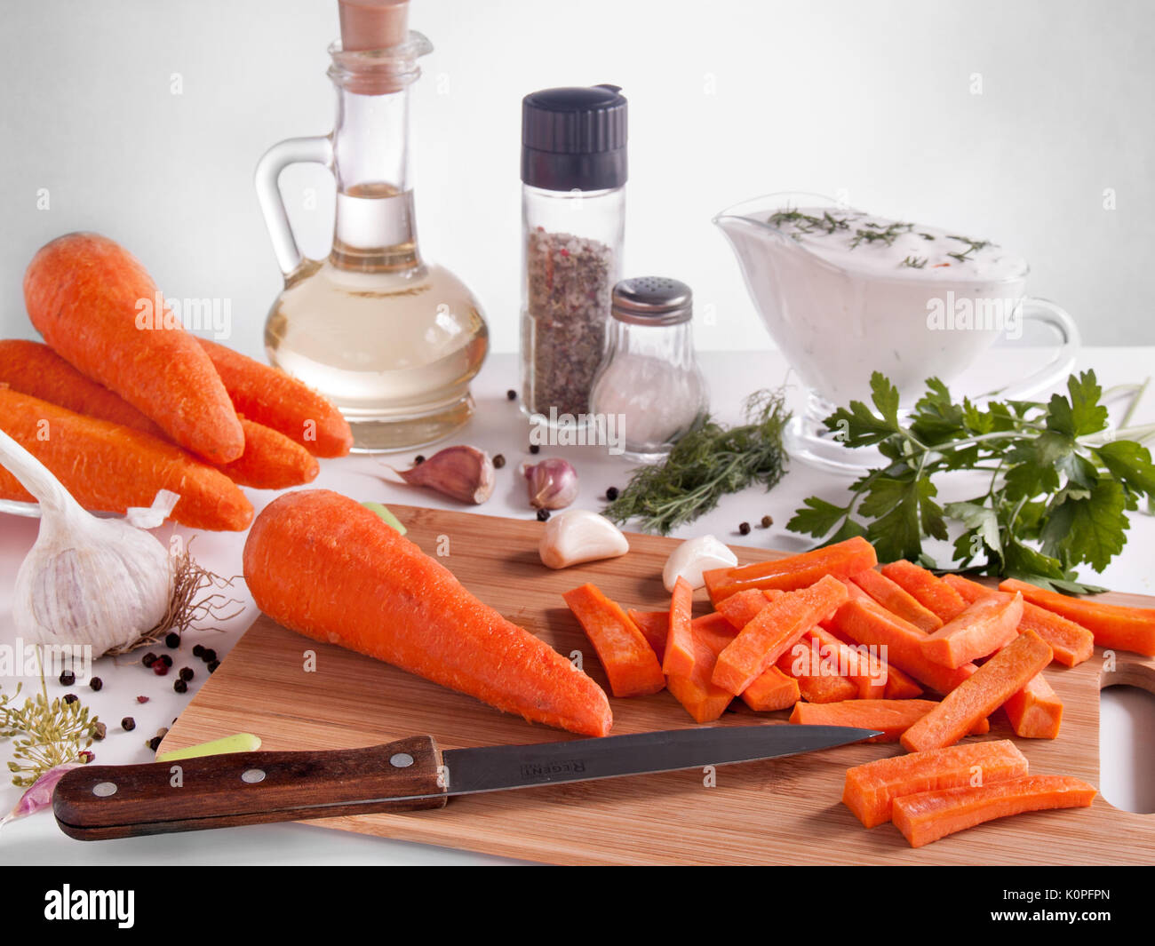 Les carottes hachées sur baguettes, entouré de verdure, persil, aneth, l'ail, le poivre, l'huile végétale dans un flacon avec un bouchon, le poivre et le sel dans des bocaux Banque D'Images