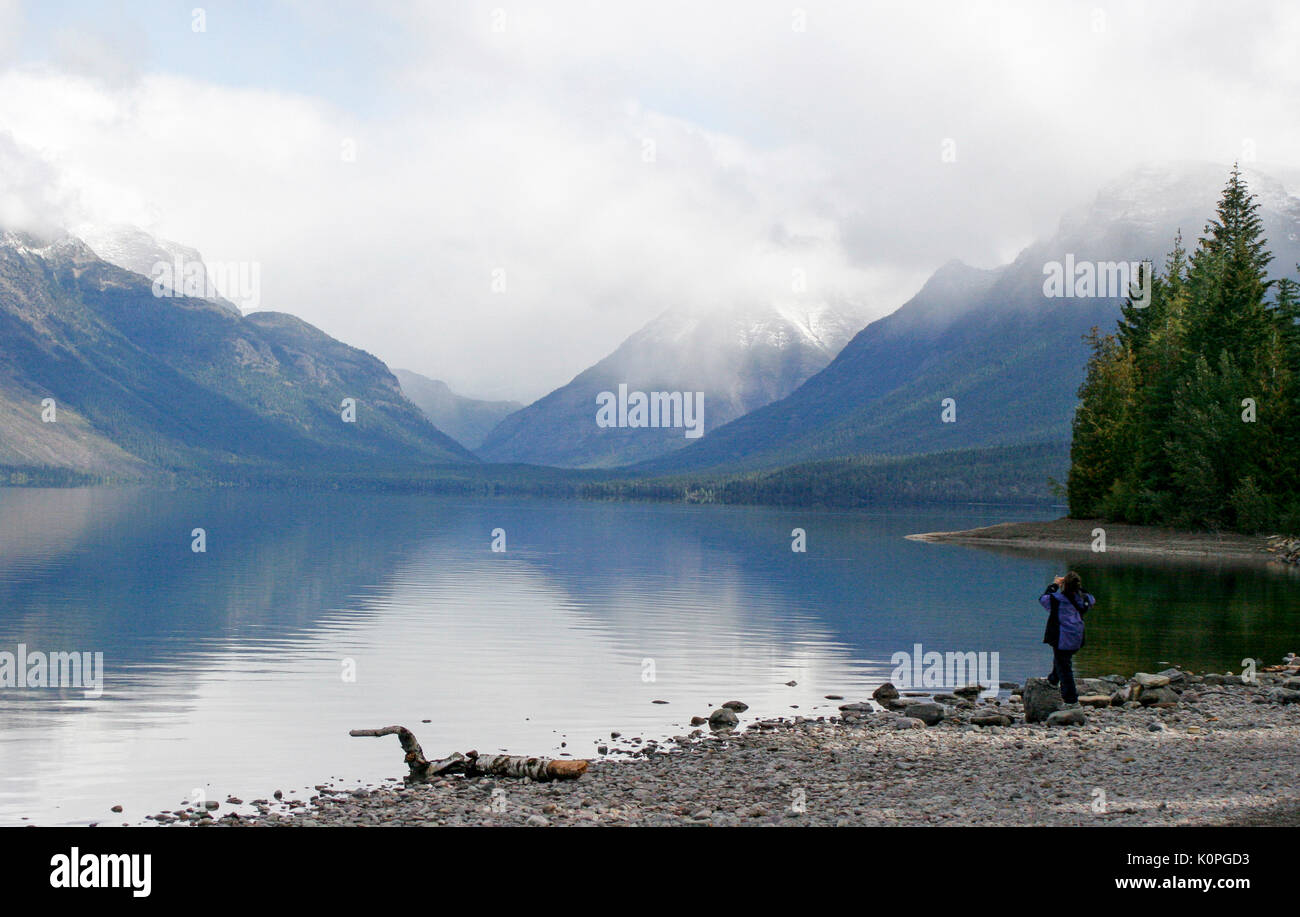 WOMAN PHOTOGRAPHING VUE SUR LE LAC ET LES MONTAGNES SUR LA RIVE DU LAC MCDONALD - Glacier National Park, Montana Banque D'Images