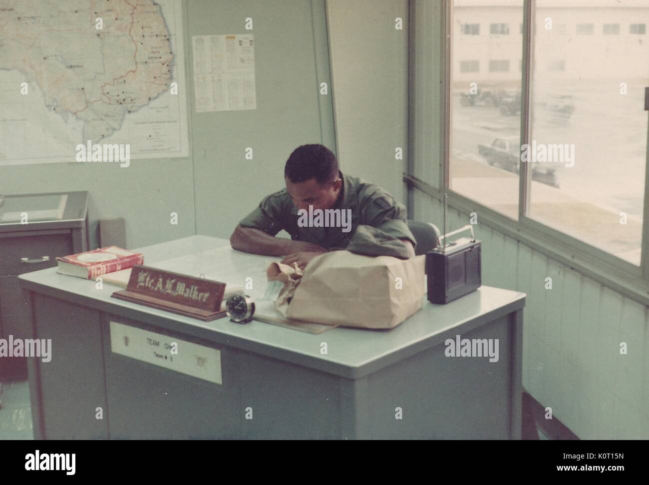 Le Lieutenant AL Walker, assis à son bureau la lecture à long Binh Post, centre de logistique, et le quartier général du commandement majeur pour United States Army Vietnam, Vietnam, 1970. Banque D'Images