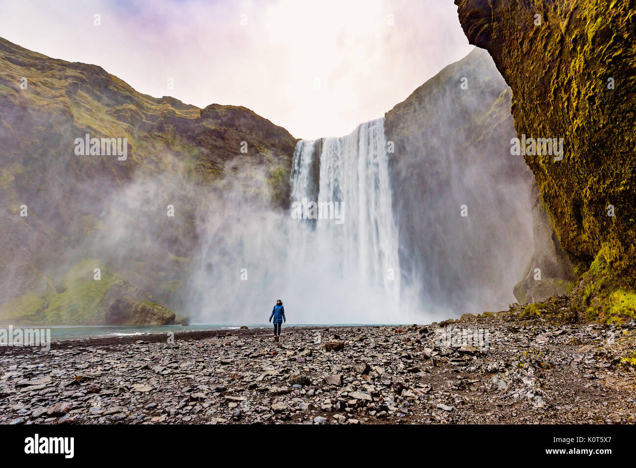 Jeune femme debout devant une cascade Skogafoss, Islande Banque D'Images