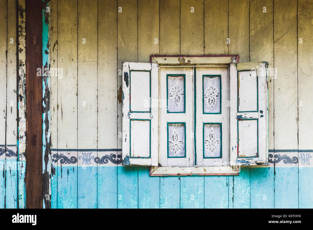 Old vintage avec fenêtre en bois les volets et les rideaux sur maison de style traditionnel indonésien. Mur peint texturé Banque D'Images