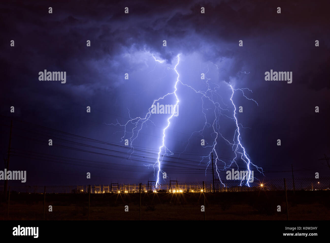 Des éclairs fréquents entre nuages et terre frappent une sous-station électrique alors que des orages de mousson se déplacent dans le désert de Phoenix, en Arizona Banque D'Images