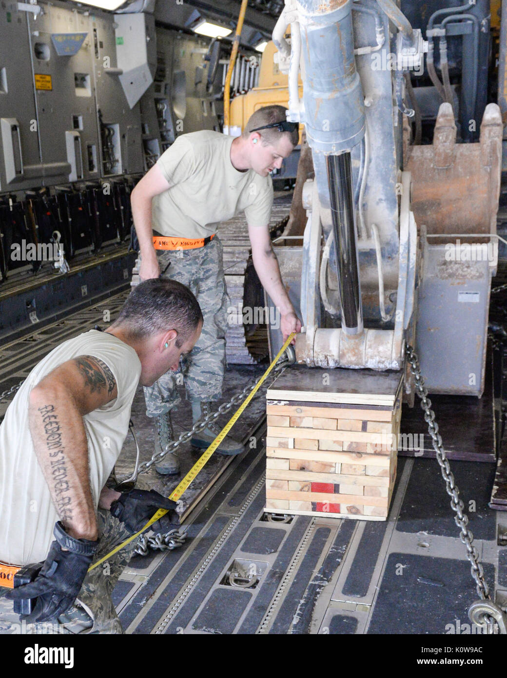 Les cadres supérieurs de l'US Air Force, Jace aviateur, permanent et le sergent. Timothy Lees, agenouillée avec ruban à mesurer, les deux artisans du transport aérien affecté à la 8e Escadron expéditionnaire de la mobilité de l'air, prendre des mesures pour s'assurer que l'équipement chargé dans un C-17 Globemaster III est correctement positionné à Al Udeid Air Base, Qatar, le 7 août 2017. La 8ème SEGO a travaillé aux côtés du corps expéditionnaire sa 557ème escadron Cheval Rouge pour charger une pelle dans un livre 50 000 avions C-17 Globemaster III pour le transport vers une destination inconnue dans la zone de responsabilité. (U.S. Air National Banque D'Images