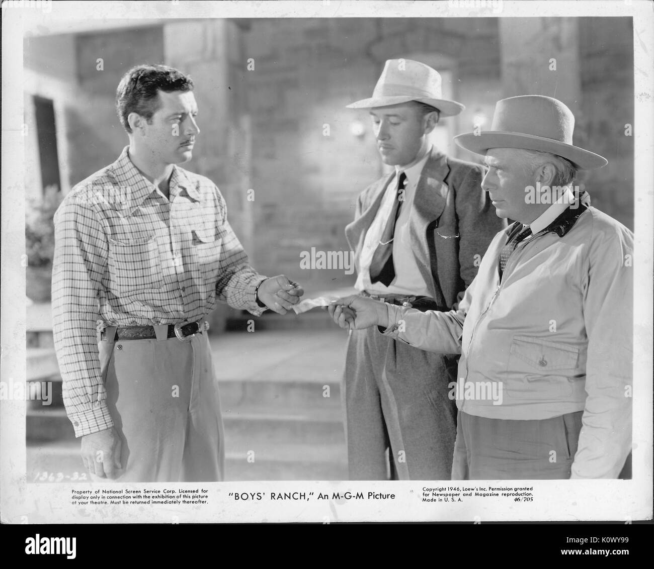 Encore une scène de film 'Boys' Ranch' (1946) film MGM, montrant trois hommes dans un caucus, avec un homme de remettre une note à l'homme en chemise à carreaux et l'autre en costume sombre et un chapeau regarde sur, 1946. Banque D'Images