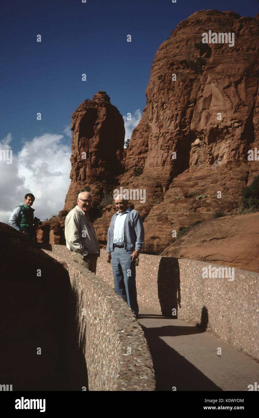 Les touristes de sexe masculin debout dans un groupe sur un trottoir de béton menant à une argile rouge mesa, moulage de grandes ombres en fin d'après-midi au soleil, Arizona, USA, 1960. Crédit photo Smith Collection/Gado/Getty Images. Banque D'Images