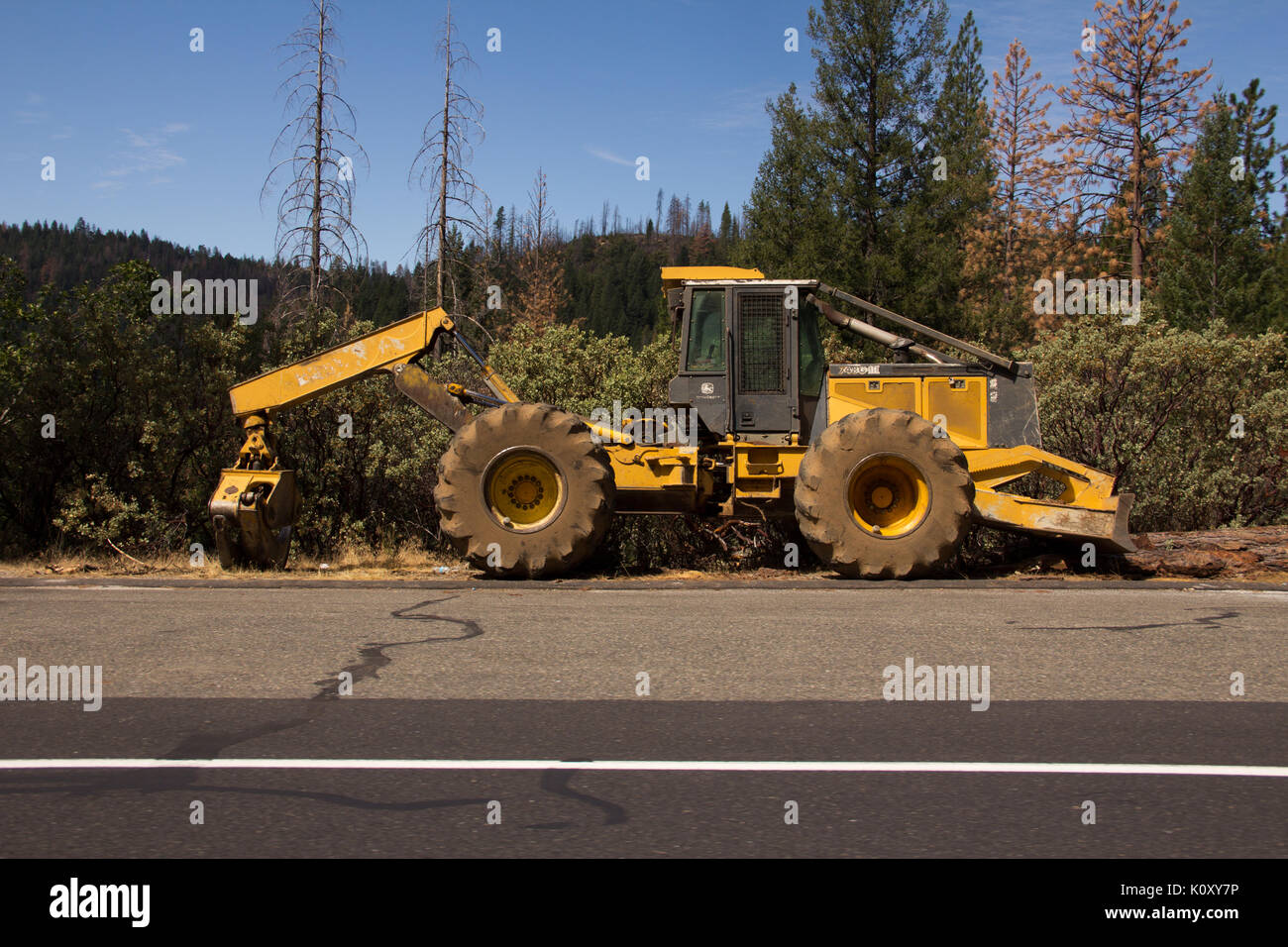 Une voiture garée sur un véhicule de construction jaune utilisé pour la prévention des incendies, en Californie Banque D'Images