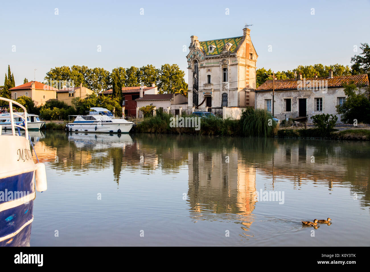 Dans un bateau long du Canal du Midi au coucher du soleil, Béziers, dans le sud de la France avec une maison de style Art Nouveau dans l'arrière-plan. Un site du patrimoine mondial depuis 1996 Banque D'Images