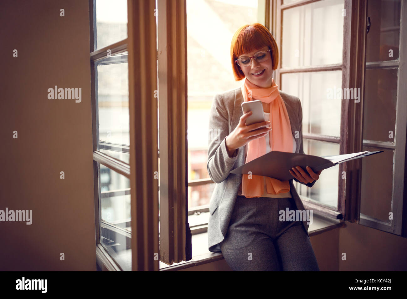 Businesswoman in office with cell phone contact business partner Banque D'Images
