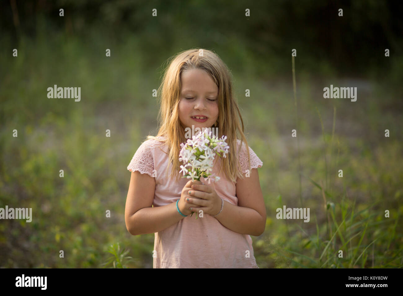 Little girl with bouquet dans la forêt Banque D'Images