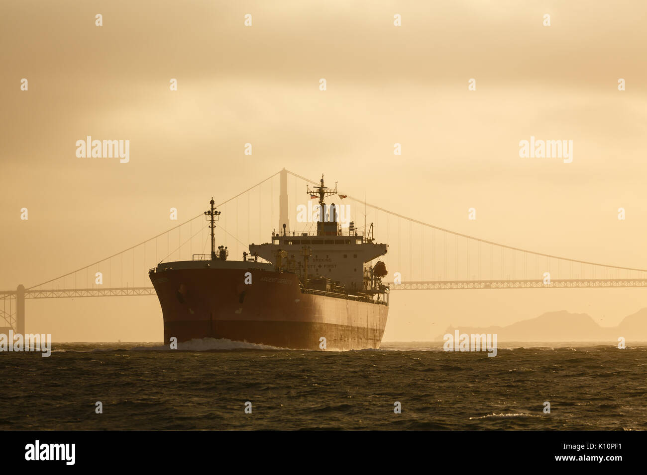 Navire pétrolier géant se glisse sous le golden gate bridge au coucher du soleil vers la mer Banque D'Images
