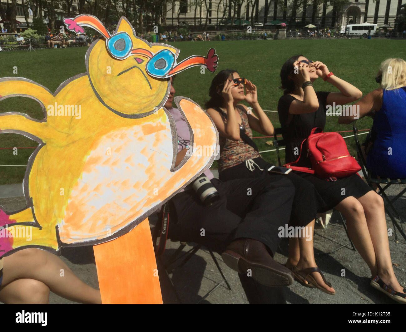 Des milliers de curieux se rassemblent dans Bryant Park pour regarder l'éclipse solaire partielle se produisant à New York Lundi, 21 août, 2017. New York n'est pas dans la bande de totalité avec la lune ne couvrant que presque 72 p. 100 du soleil pendant les 2:44pm maximum. Kat Eclipse, dessiné par Frances M. Roberts se joint à la foule pour regarder l'éclipse. (© Frances M. Roberts) Illustration Banque D'Images