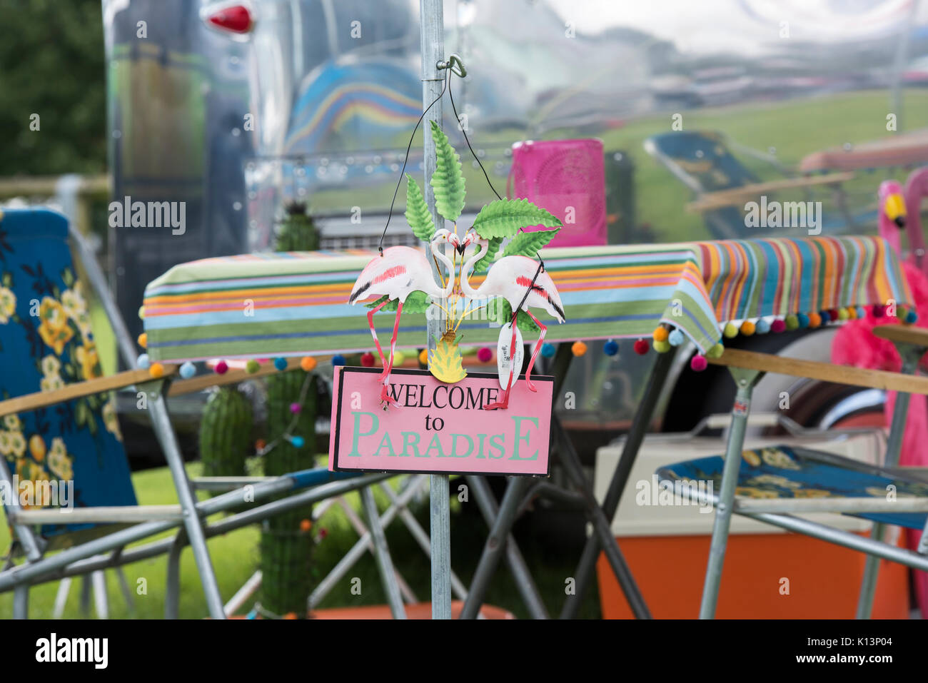 Bienvenue au paradis 'kitsch' camping signe devant une caravane Airstream vintage retro à un festival. UK Banque D'Images