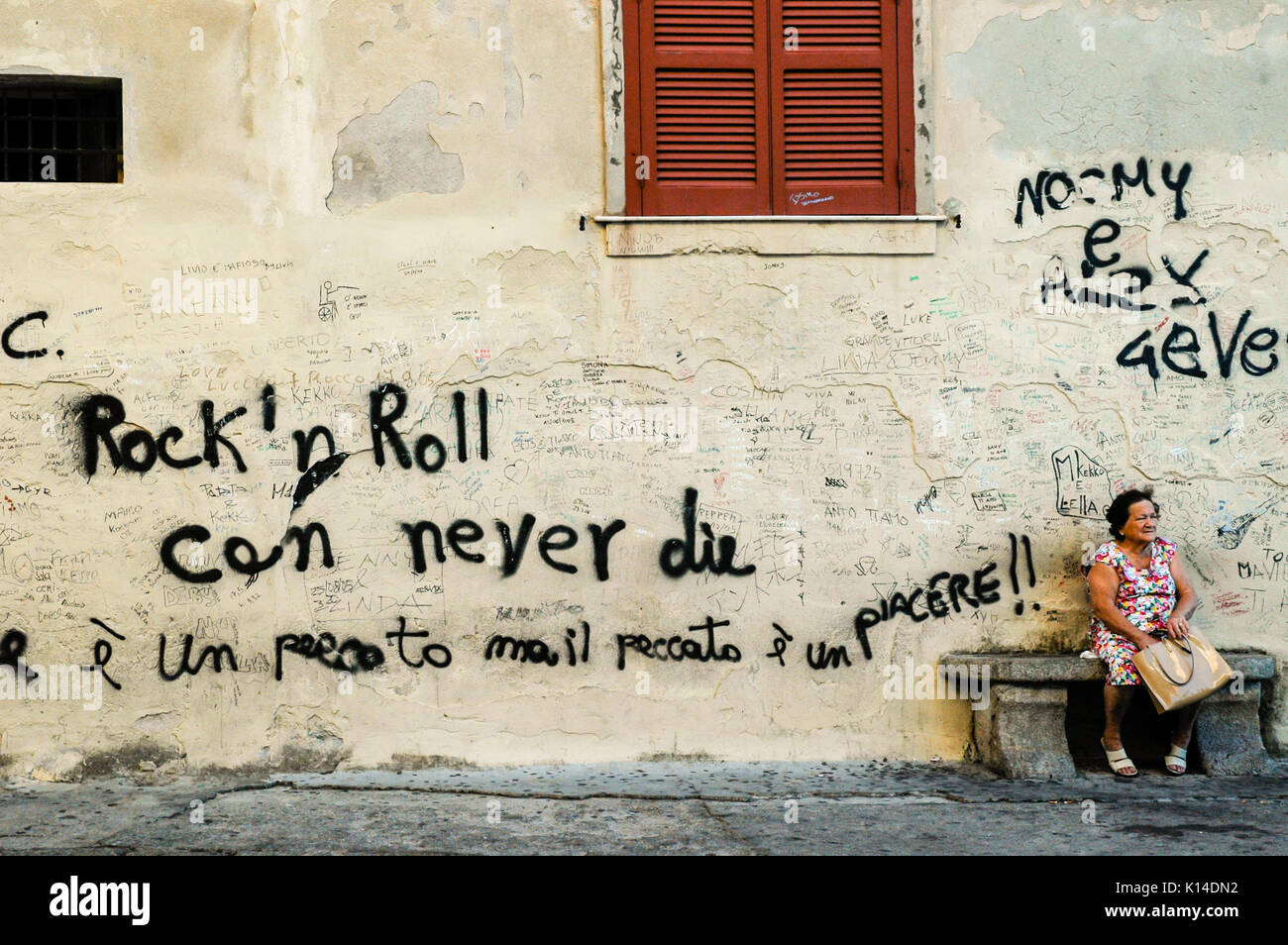 TROPEA, Calabre, Italie, avril 2014 : des graffitis dans une ancienne ville italienne de Calabre. Vieille Femme assise à côté d'un mur avec les mots "Rock'n roll peut nev Banque D'Images