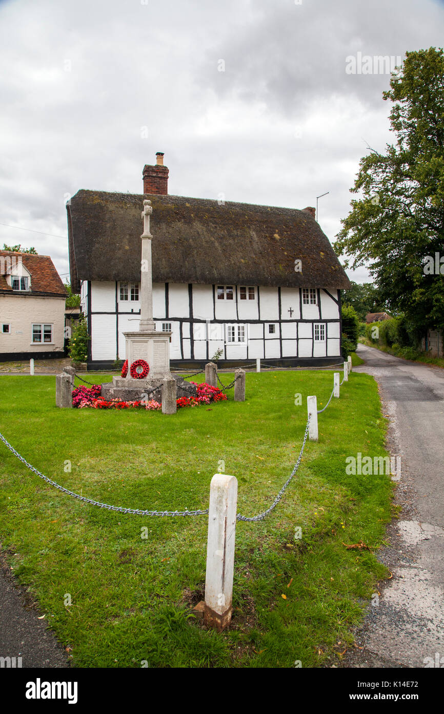 War Memorial debout sur le village vert avec le noir et blanc 2015 maison à colombages au toit de chaume derrière à Dorchester on Thames Oxfordshire Banque D'Images