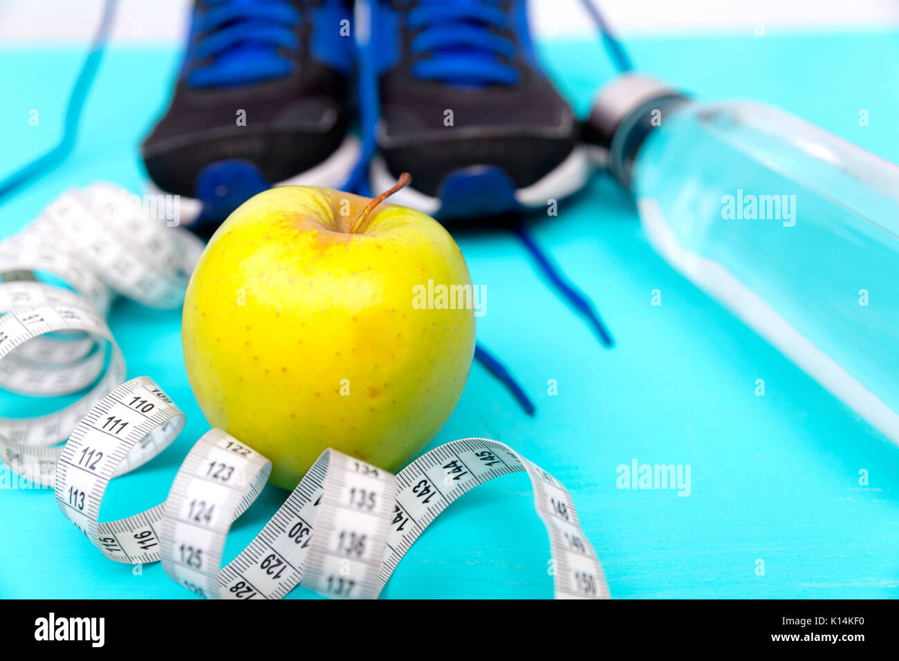 Chaussures sneaker sport avec un ruban à mesurer, Apple et une bouteille d'eau sur fond bleu. Fitness, un mode de vie sain et actif concept Banque D'Images