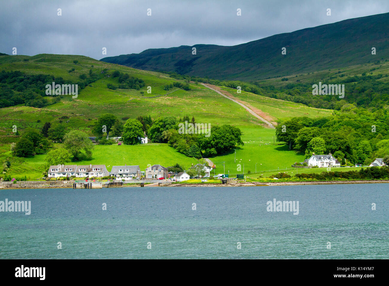 Paysage avec village de Colintraive au pied des collines d'emerald fields & woodlands & sur le rivage de Kyles de Bute, vu de l'île de Bute, Ecosse Banque D'Images