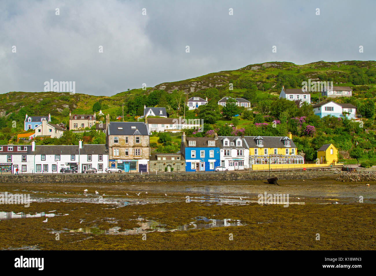 Village écossais de Tarbert avec bâtiments colorés au pied de collines boisées au bord du Loch Tarbert à marée basse, de l'Écosse Banque D'Images
