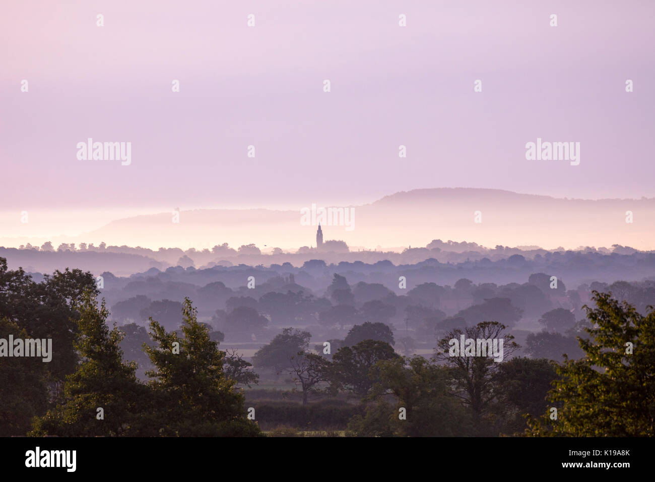 Flintshire, UK . avec une chaude journée derrière et de compensation ciel de flintshire comme le soleil commence à sortir de l'horizon et le ciel l'éclairage sur la plaine du Cheshire rose depuis les contreforts de flintshire Banque D'Images