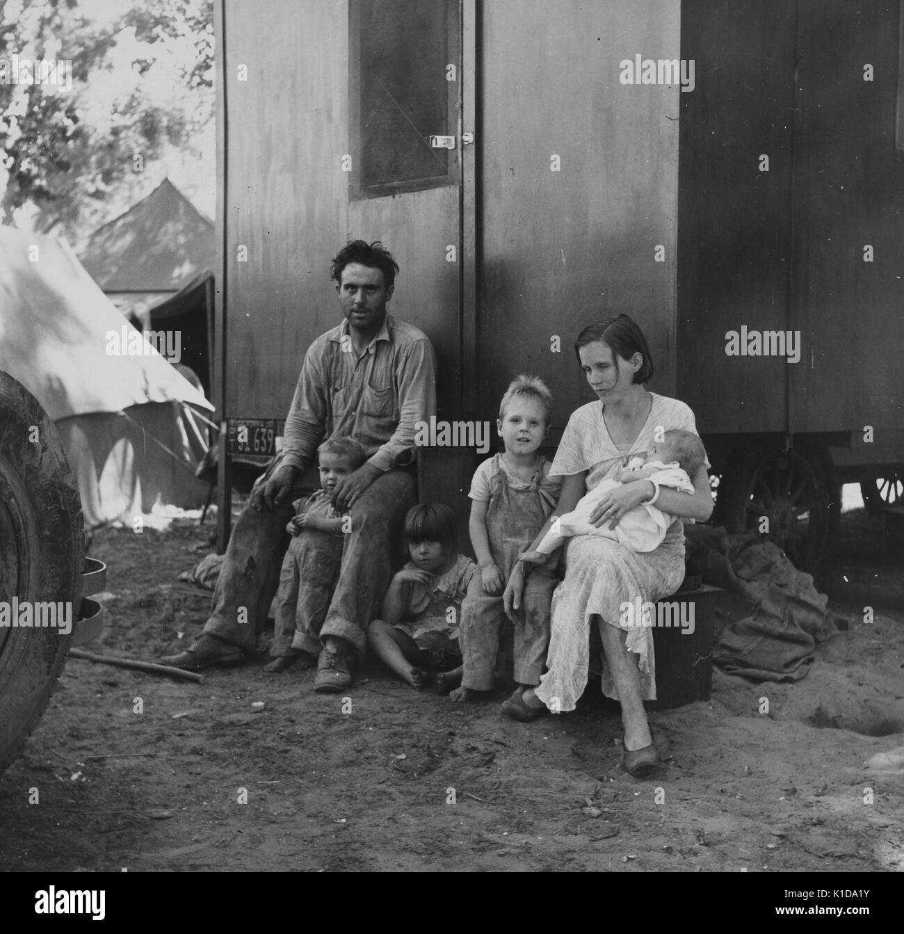 Un travailleur migrant, sa jeune femme et quatre enfants qui se reposent en dehors de leur logement temporaire, situé dans un camp de migrants, Marysville, Californie, 1935. De la bibliothèque publique de New York. Banque D'Images