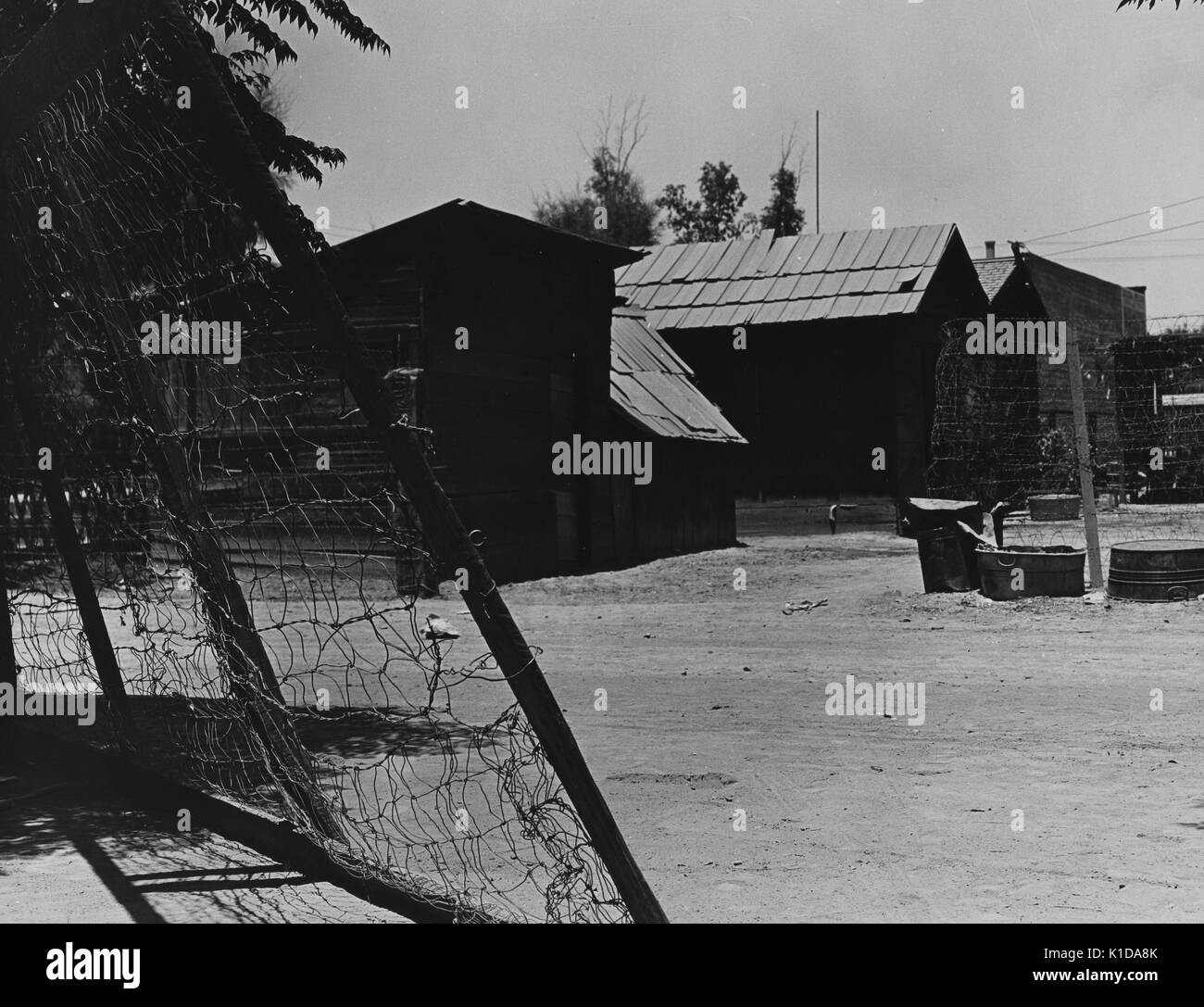 Bâtiments de ferme en bois, dans une rangée, entouré par des pièces d'une clôture et plusieurs seaux d'étain, de l'imperial valley, brawley, Californie, 1935. à partir de la bibliothèque publique de new york. Banque D'Images