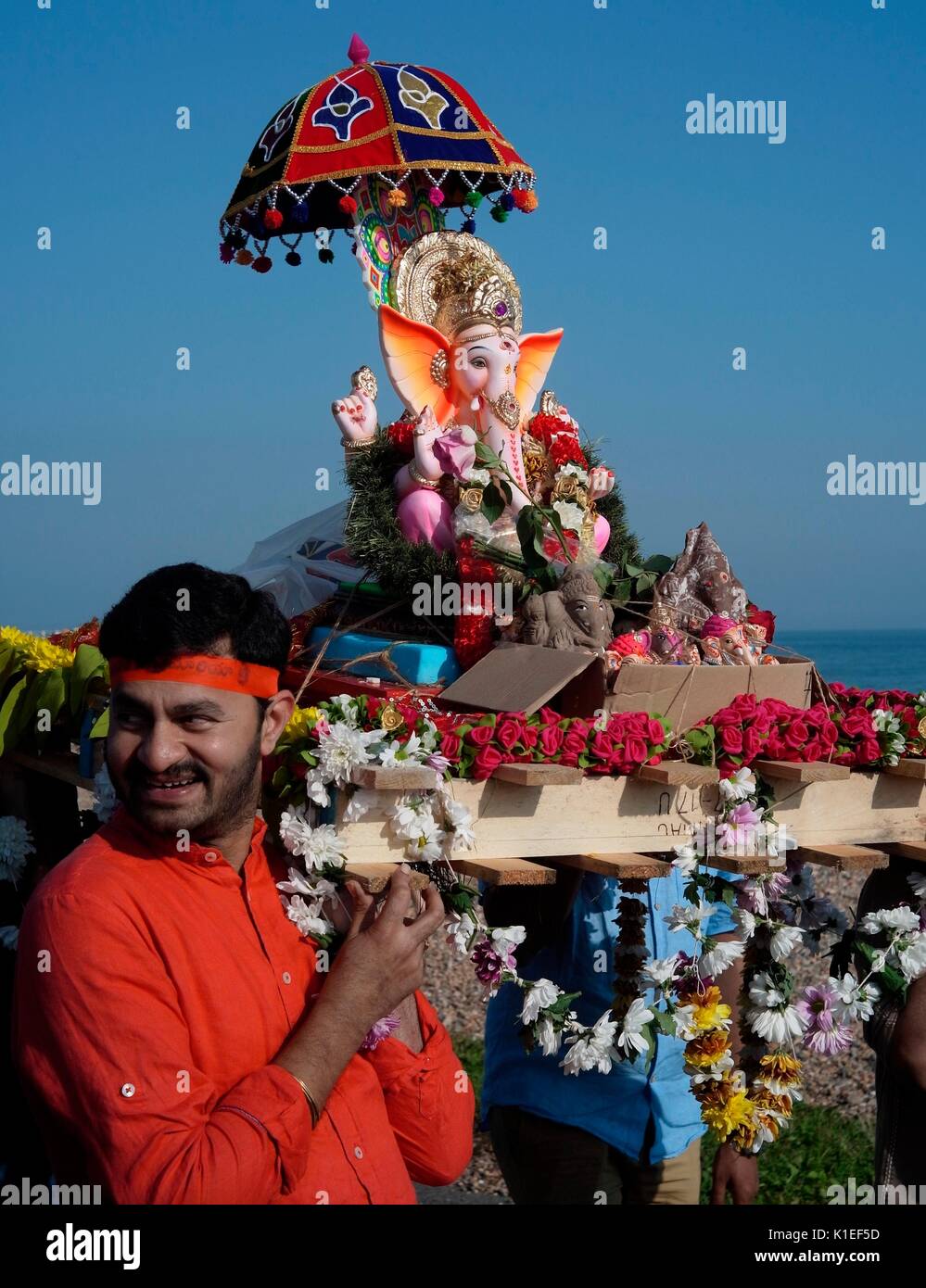 Worthing, Royaume-Uni. 27th août 2017. Fête de Ganesh au Royaume-Uni - les membres de la communauté hindoue locale portent un modèle de Lord Ganesh le long de la plage jusqu'à la Manche. Également connu sous le nom de Ganesh Chaturthi, l'important festival célèbre le fils à tête d'éléphant de Lord shiva et de la déesse Parvati, symbole de sagesse, de prospérité et de bonne fortune. Le modèle est fait de plâtre de paris et se dissout dans l'eau de mer. Credit: Photo: Jonathan Eastland/Ajax/Alamy Live News Banque D'Images
