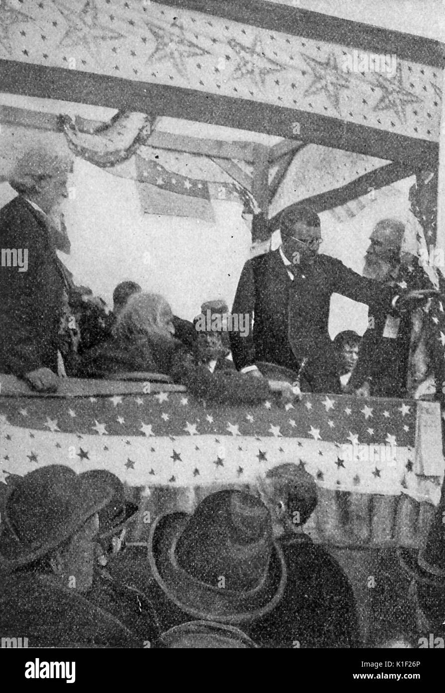 Theodore Roosevelt debout sur une scène surélevée, couverts, avec des bannières couvertes dans les étoiles, faisant campagne pour une foule d'hommes en chapeaux, 1900. Banque D'Images