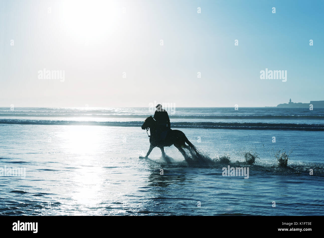 Silhouette d'un cavalier sur la plage au coucher du soleil. High key image. Banque D'Images