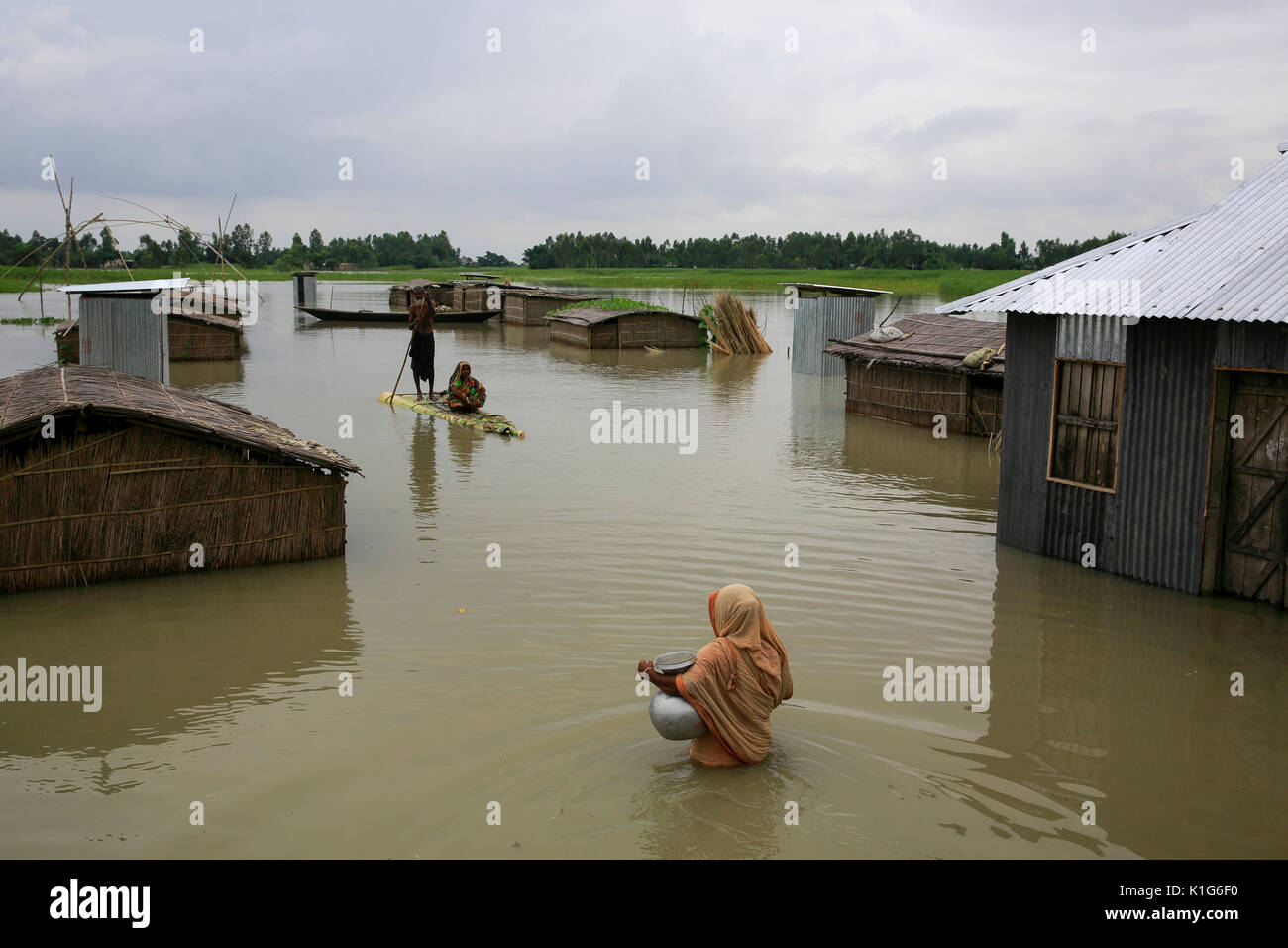 Une femme avec de l'eau potable recueillies à partir d'une pompe à main inondée dans un village de l'upazila Chilmari à Kurigram, Bangladesh Banque D'Images