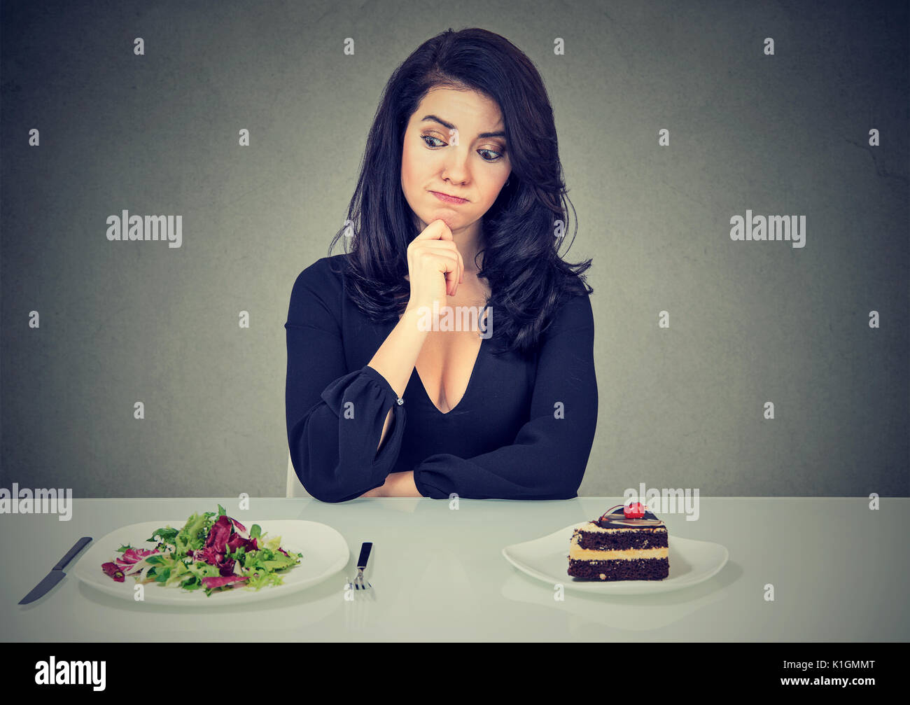 Dieting concept, belle jeune femme de choisir entre des aliments sains et savoureux gâteau Banque D'Images