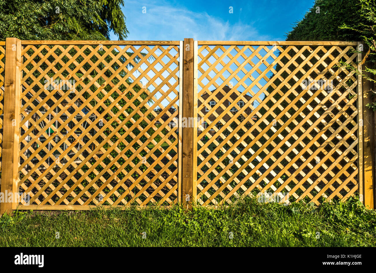 Voir à travers deux treillis en bois, panneaux de clôture, avec une chambre à l'arrière-plan, de manière à ne pas masquer la vue. Angleterre, Royaume-Uni. Banque D'Images