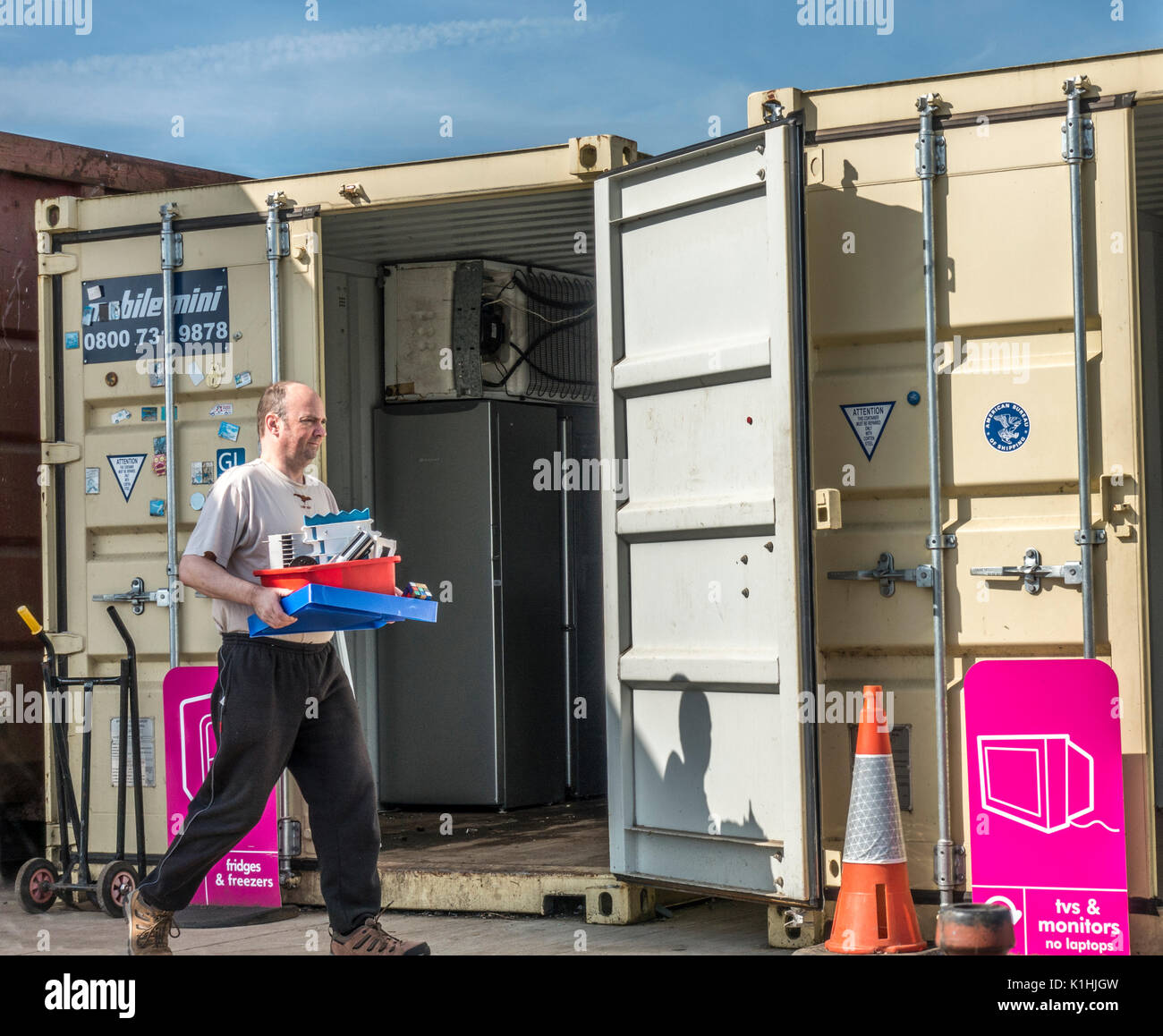 Homme portant des articles en plastique pour disposer d'au le conseil municipal de recyclage / centre / refuser astuce en Bourne, Lincolnshire, Angleterre, Royaume-Uni. Banque D'Images