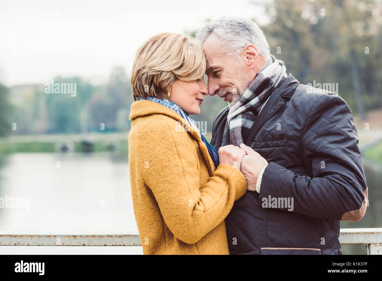 Close-up portrait of beautiful mature couple debout et tenant les mains près de lake in autumn park Banque D'Images