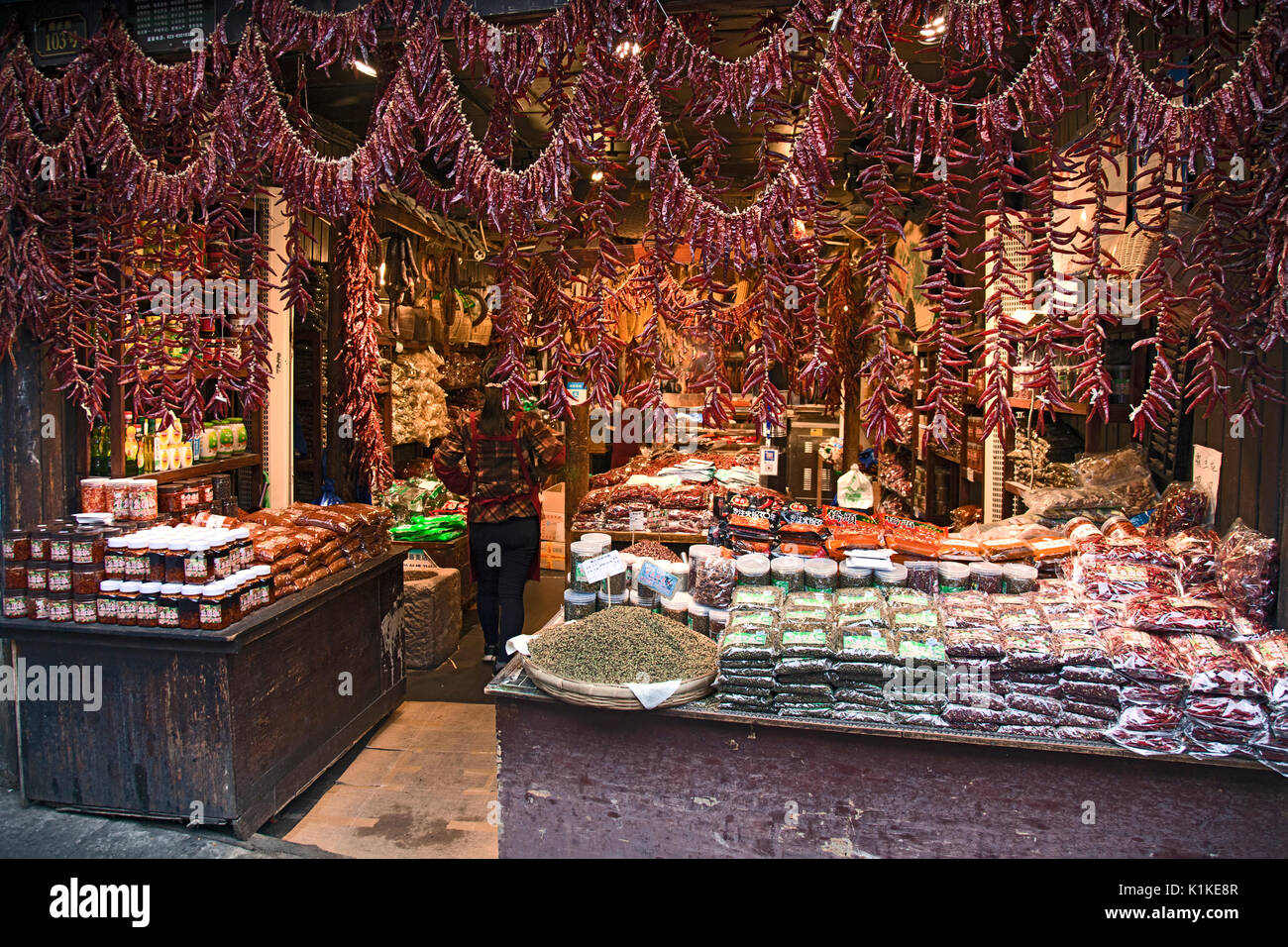 Boucles de poivrons rouges décorent l'entrée d'une boutique d'épices et de produits alimentaires dans la rue principale de la vieille ville de Ciqikou, Chongqing, Chine. Banque D'Images