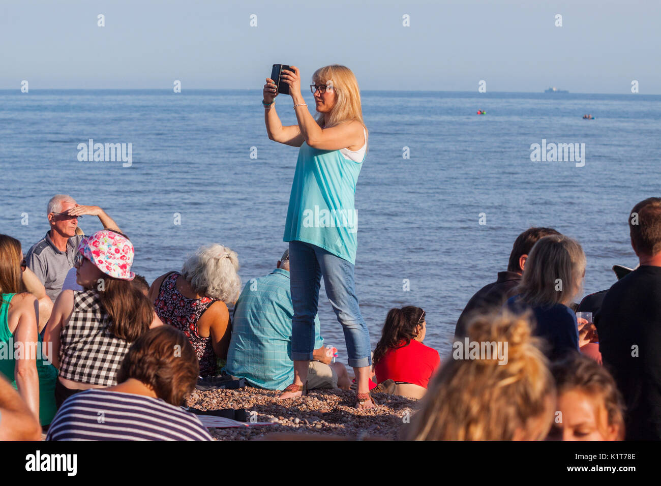 Une jeune femme prend des photos des vidéos à l'aide d'un téléphone mobile sur une plage. Banque D'Images