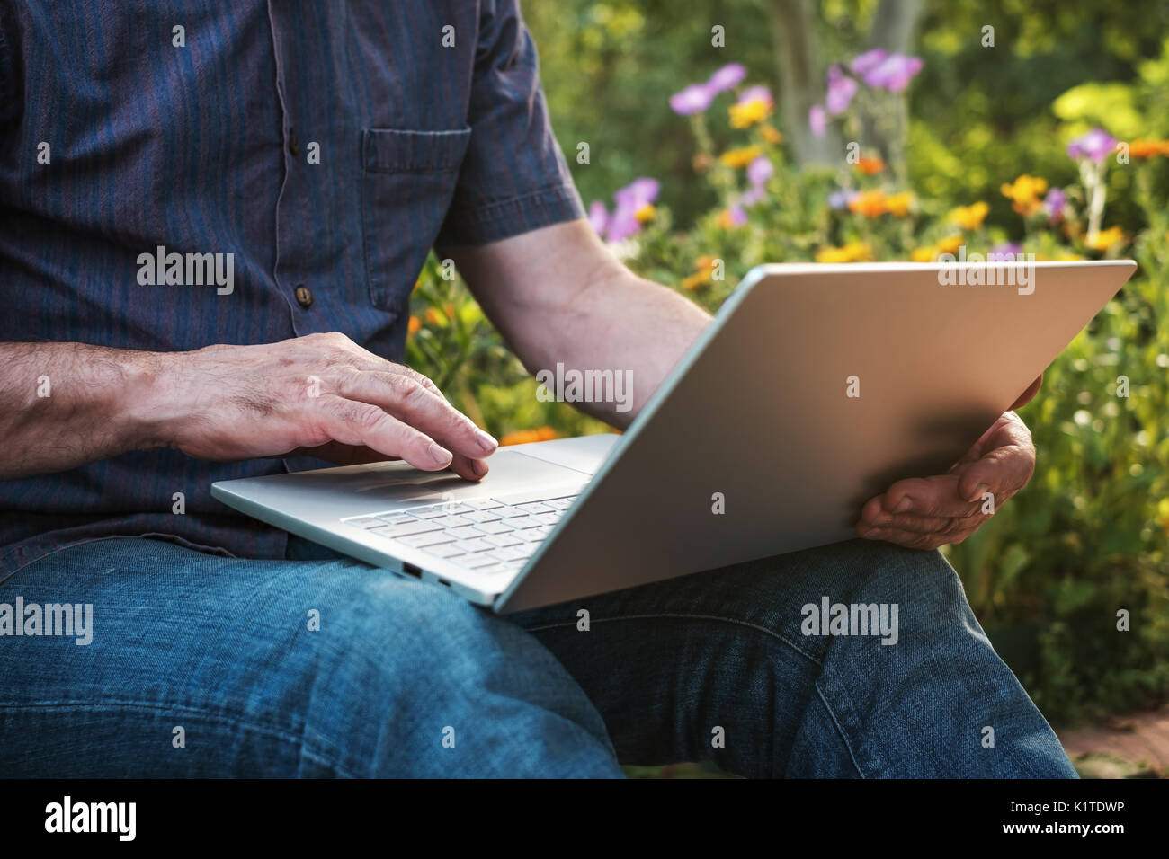 Portrait of a young man working on his laptop in jardin, ancien homme blogger saisie sur ordinateur portable Banque D'Images