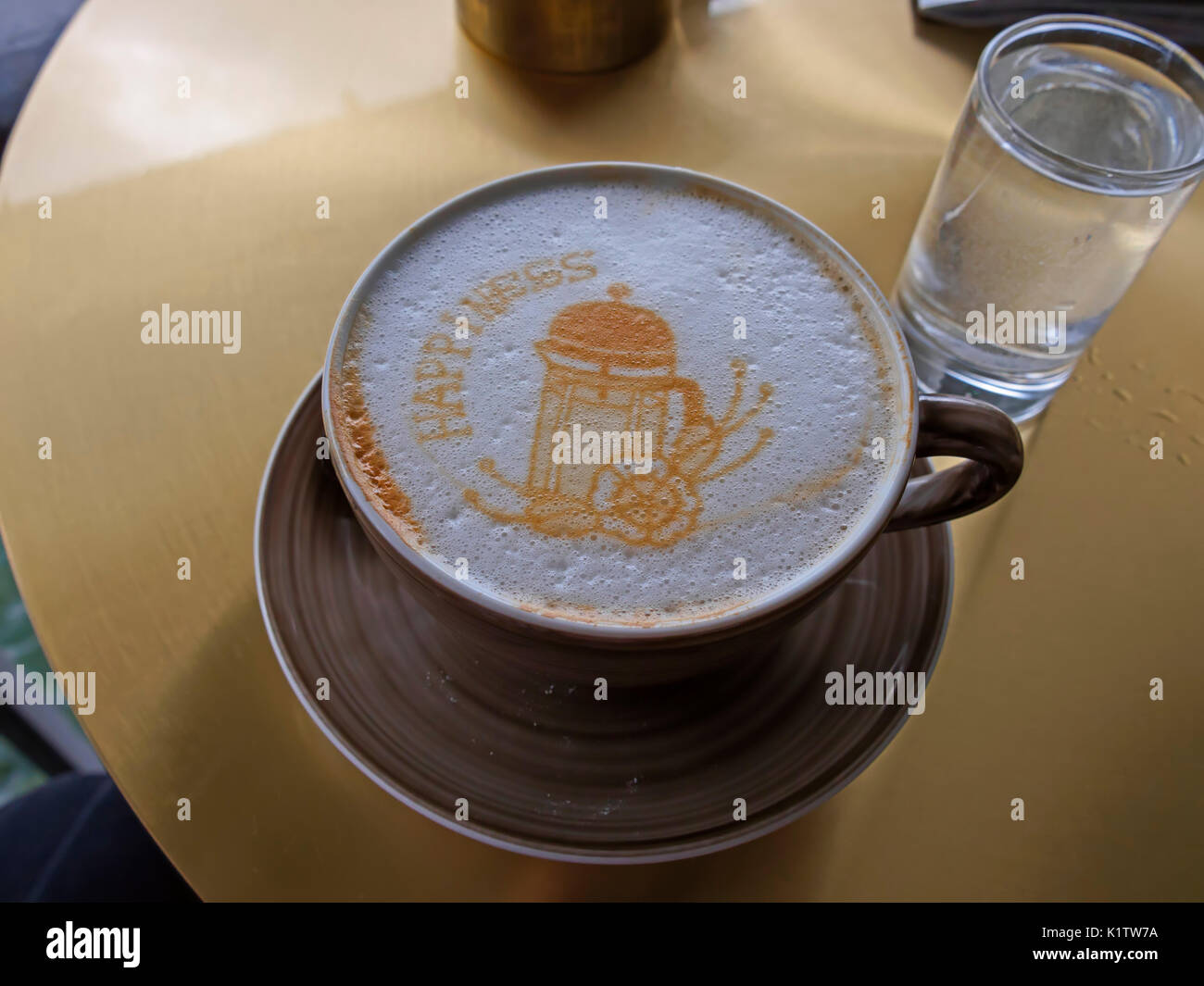 Cappuccino avec un motif dans la mousse servi avec un verre d'eau Banque D'Images
